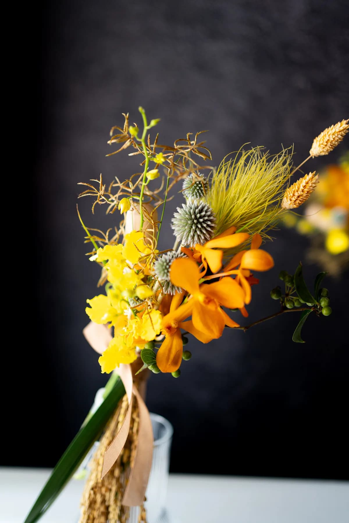 豐收鼓棒花材近拍，橘色蘭花、黃色跳舞蘭、圓刺芹與稻穗交疊