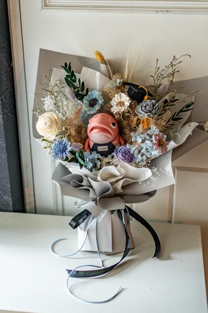 鮭女拾花「學成鮭來」霧藍色永生與乾燥花束，鮭毛先生公仔坐在花束中央