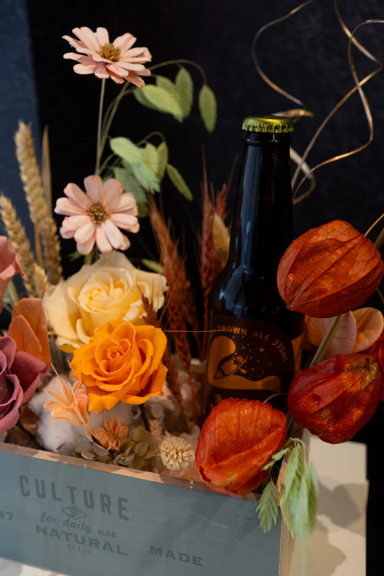 湧金啤酒永生花版本特寫——木箱裡的啤酒、玫瑰、橘色燈籠果