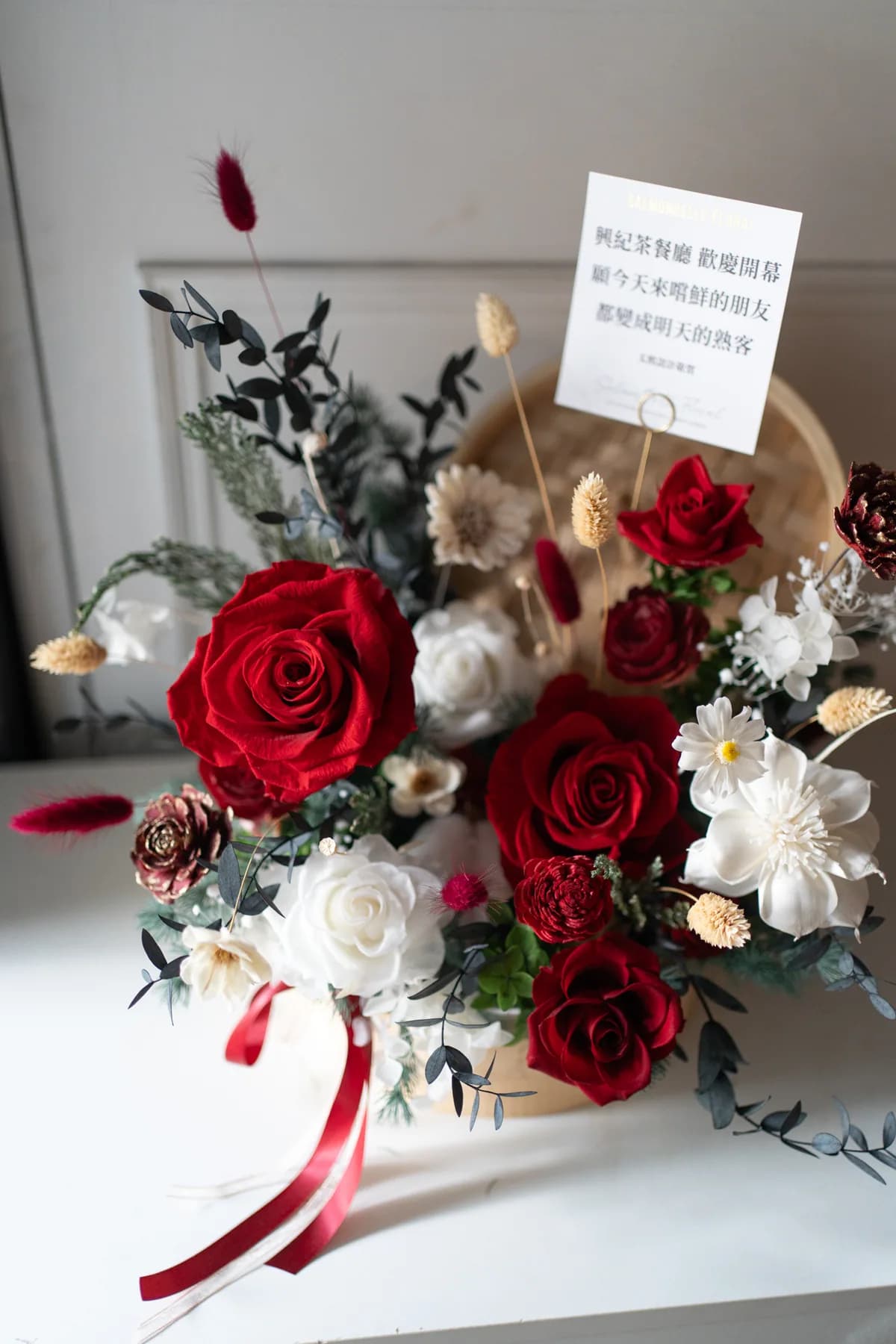 蒸籠開幕桌花全景・紅玫瑰白玫瑰永生花搭竹編蒸籠花器與紅緞帶・村家鮭女創意花禮